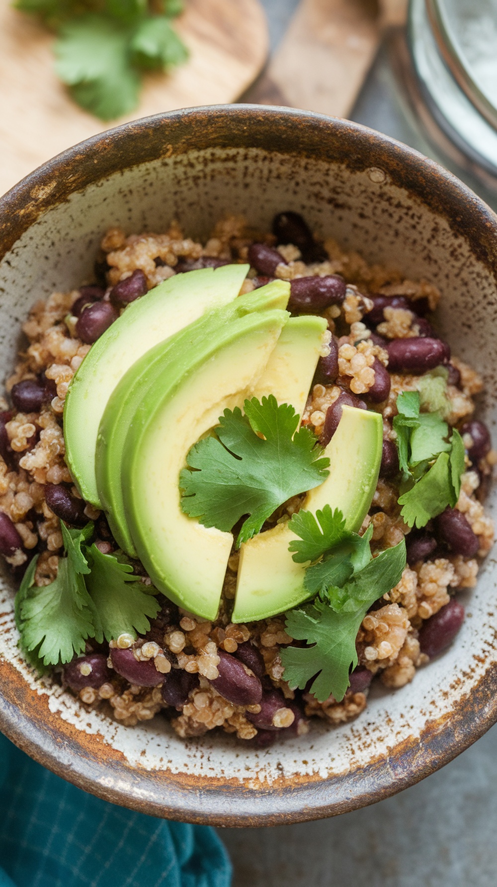 A bowl of quinoa and black beans topped with avocado slices and cilantro