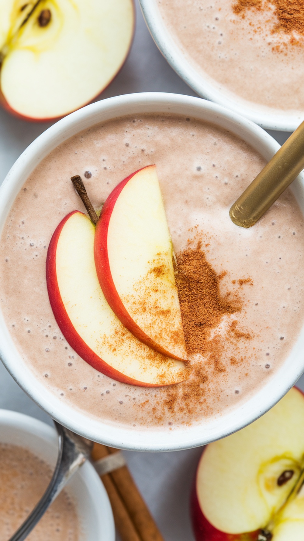 A creamy apple cinnamon oat smoothie topped with apple slices and cinnamon.