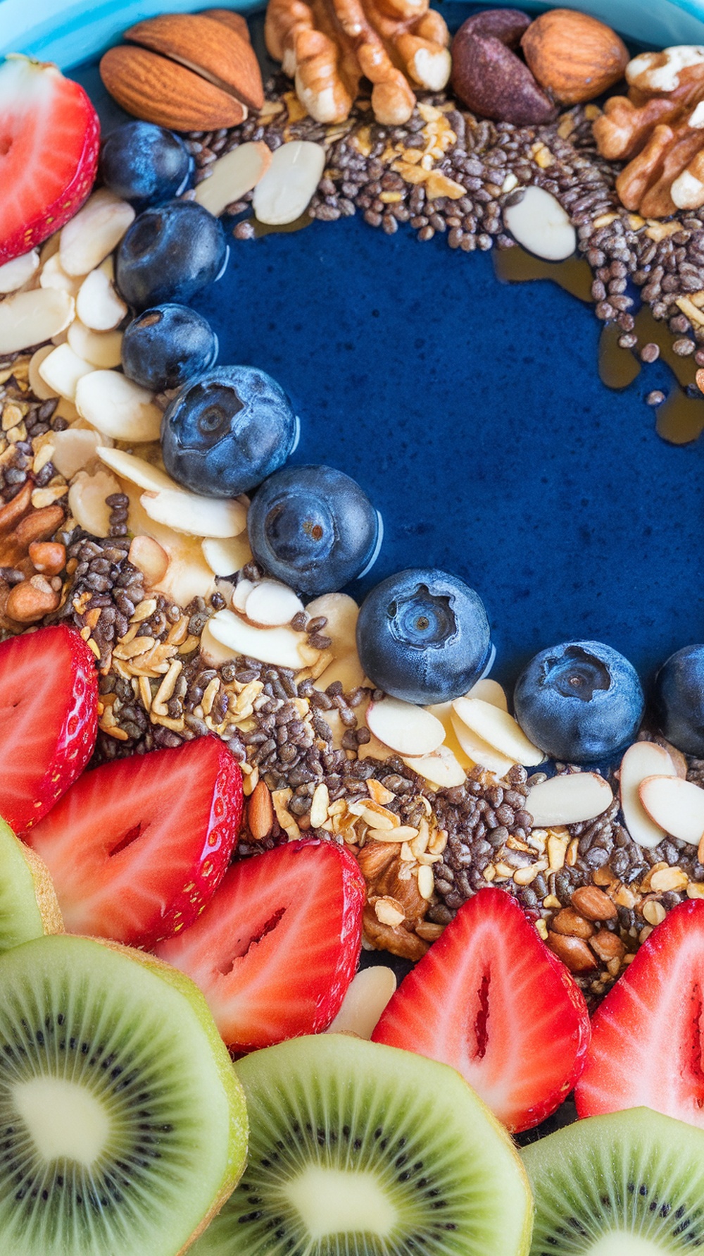 A colorful protein smoothie bowl topped with fresh fruits, nuts, and seeds.