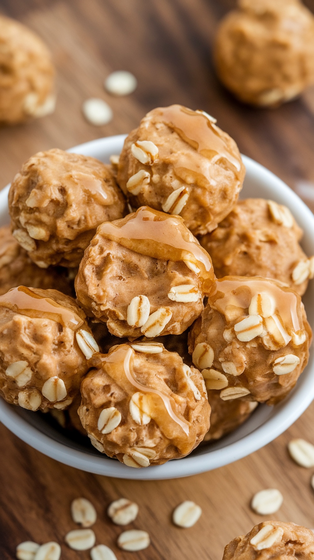 A bowl of peanut butter oat energy bites drizzled with honey and topped with oats.