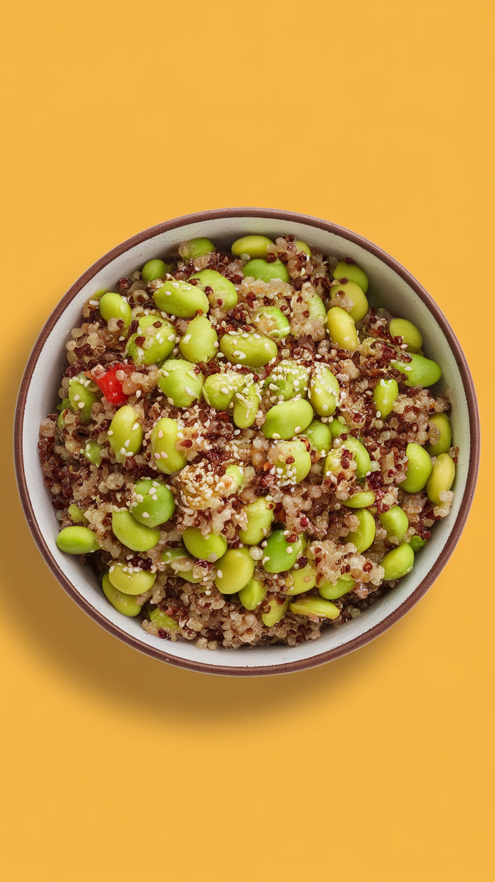 A bowl of edamame and quinoa salad with colorful ingredients.